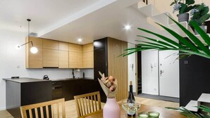 Eine moderne Küche mit Holzausstattung, einem Esstisch mit Stühlen und einer Blumenvase.