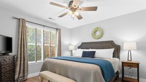 A bedroom with a bed, a bench, a nightstand, a television, and a ceiling fan. - Close to HWY 76 Strip!  Great Location! (Branson)