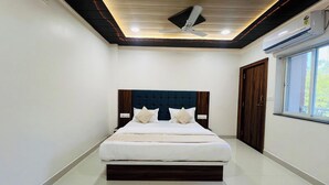 A bedroom with a bed, a ceiling fan, and a window. - Hotel Hari Palace (Ujjain)