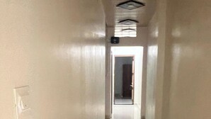 A long, narrow hallway with a shiny floor and a door at the end. - Hotel Hari Palace (Ujjain)