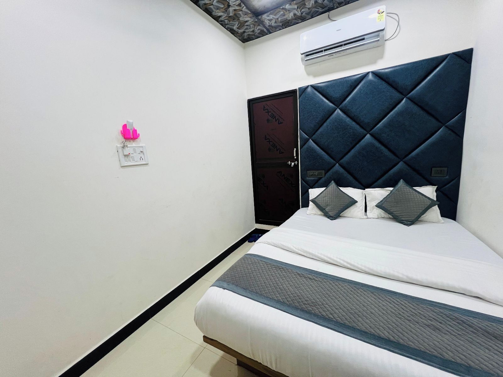 Una habitación de hotel con cama, armario, equipo de aire acondicionado y l ámpara de pared.