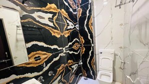 A bathroom with a black and gold marble backsplash, a white sink, a toilet, and a bidet. - Hotel Hari Palace (Ujjain)