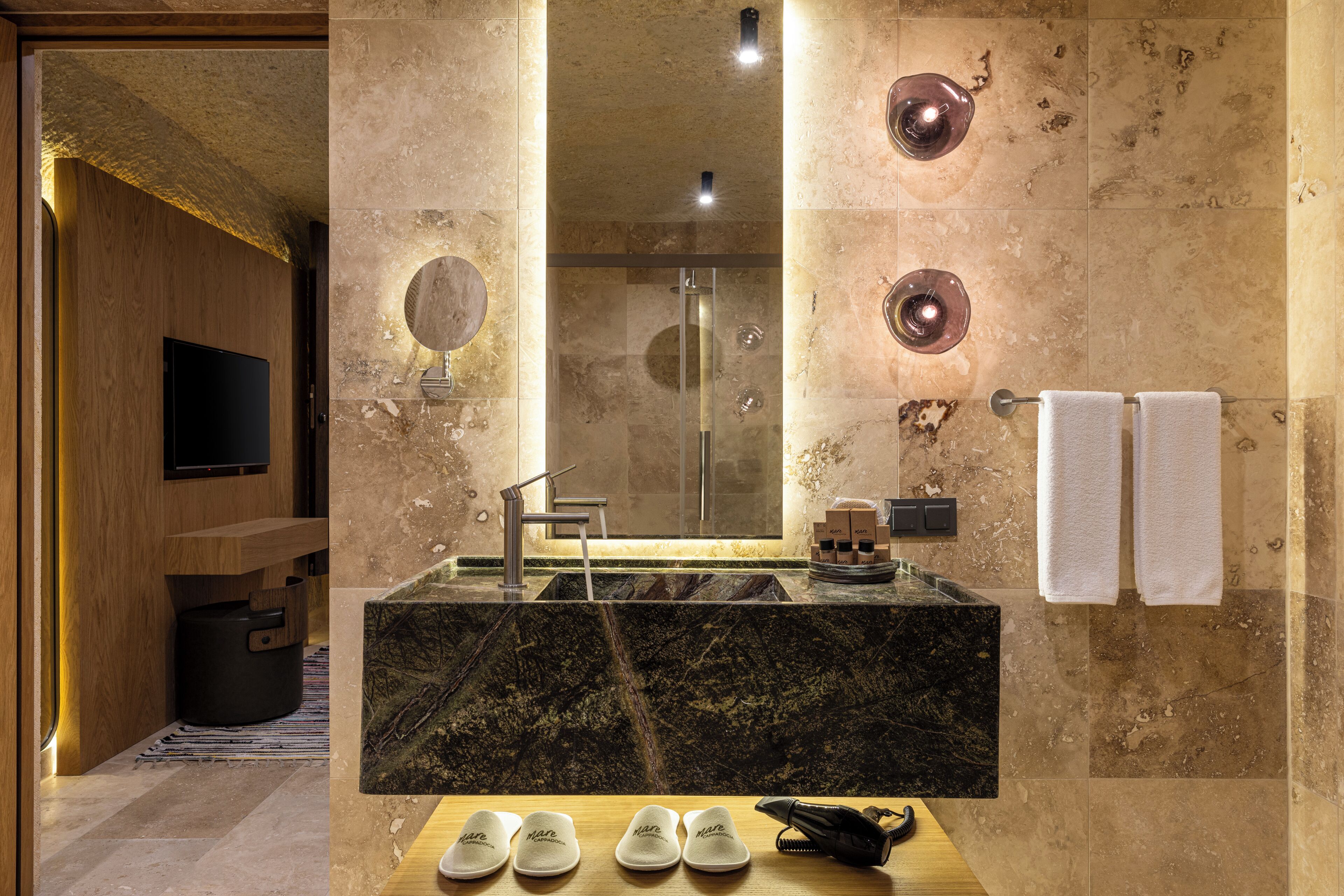 A modern bathroom with a marble sink, a large mirror, a shower, and a wooden vanity.