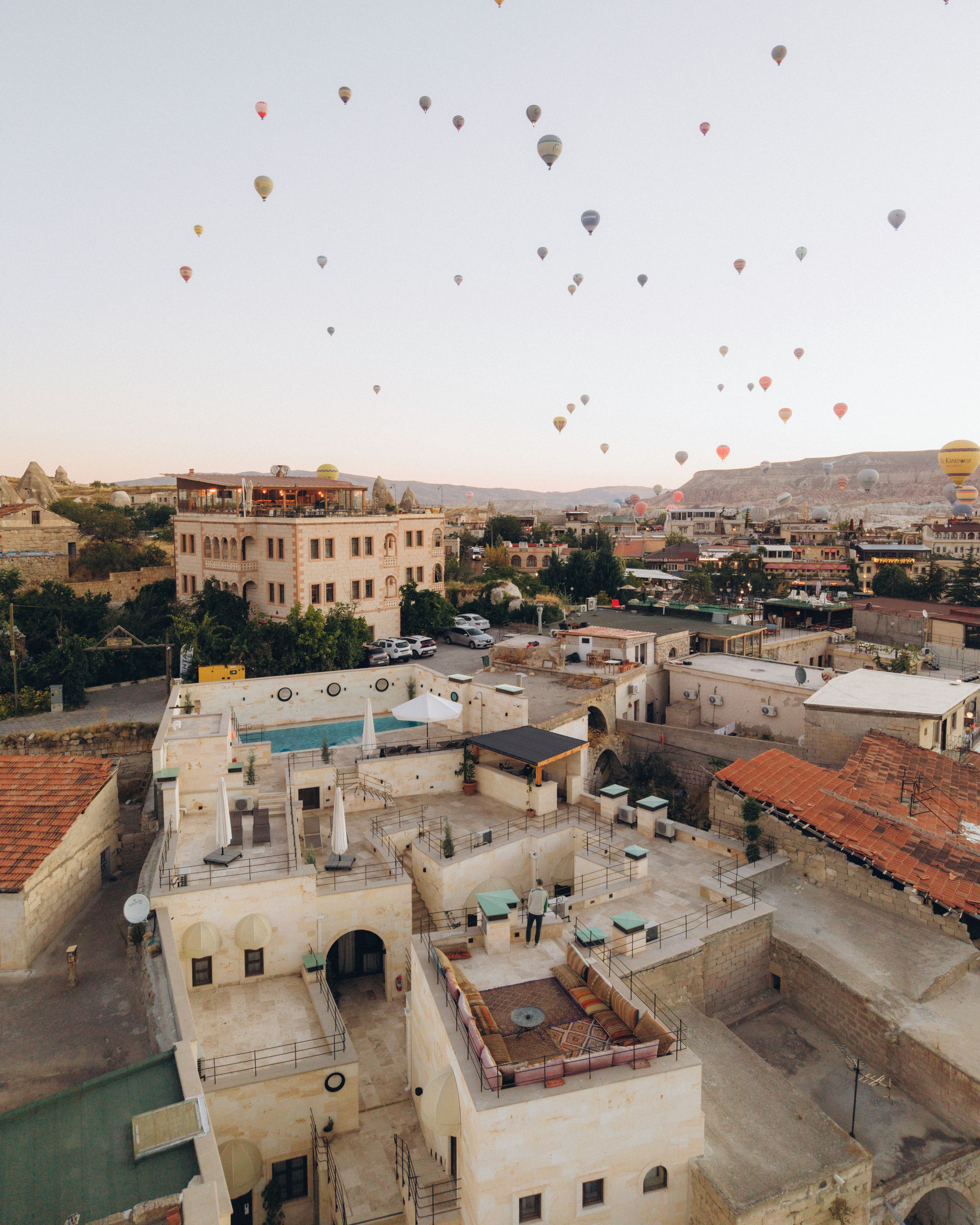 A rooftop terrace with a view of the cityscape and hot air balloons in the sky.