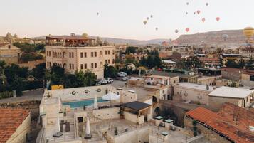 A rooftop terrace with a view of the cityscape and hot air balloons in the sky.
