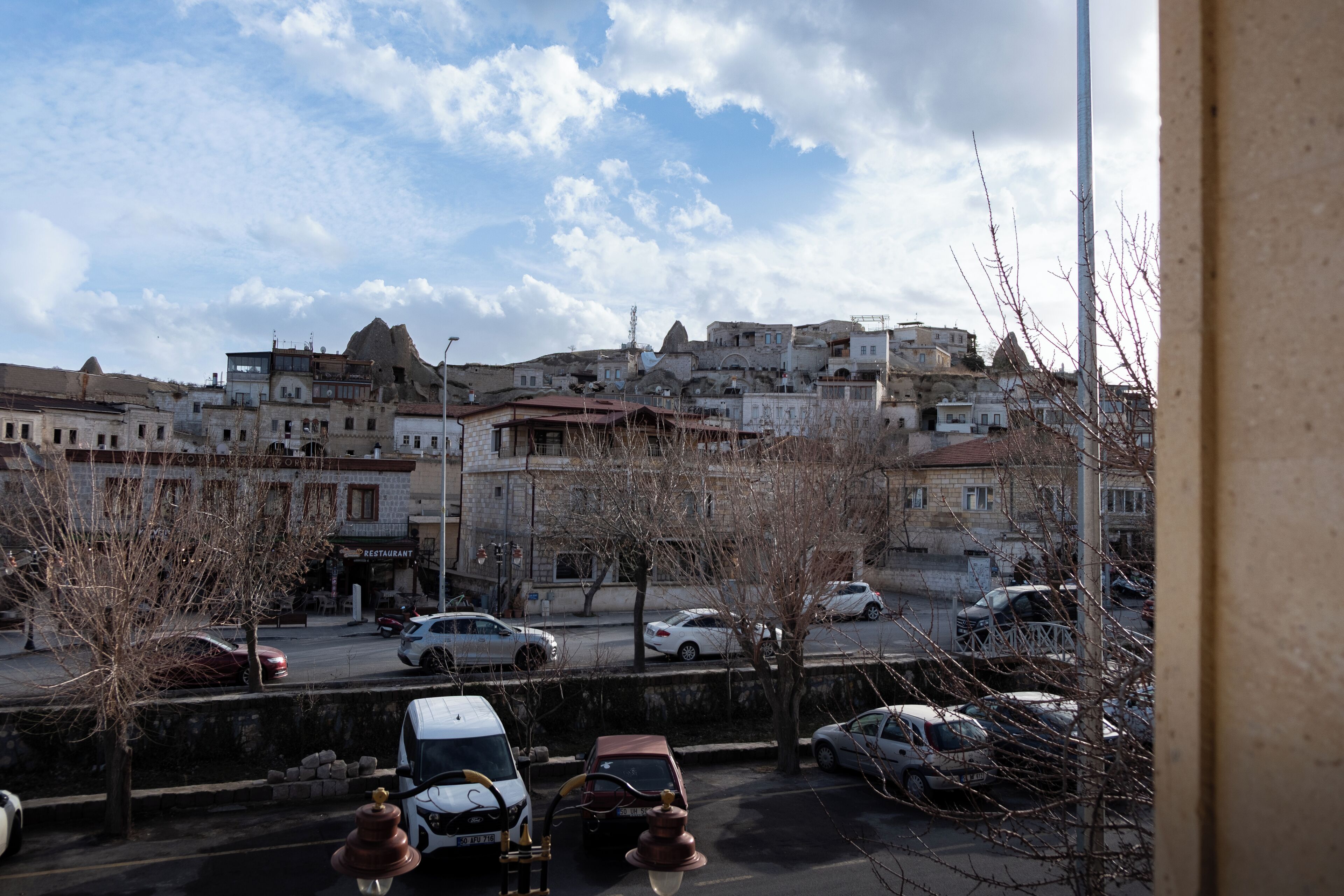 A view of a cityscape with buildings, parked cars, and a clear sky.