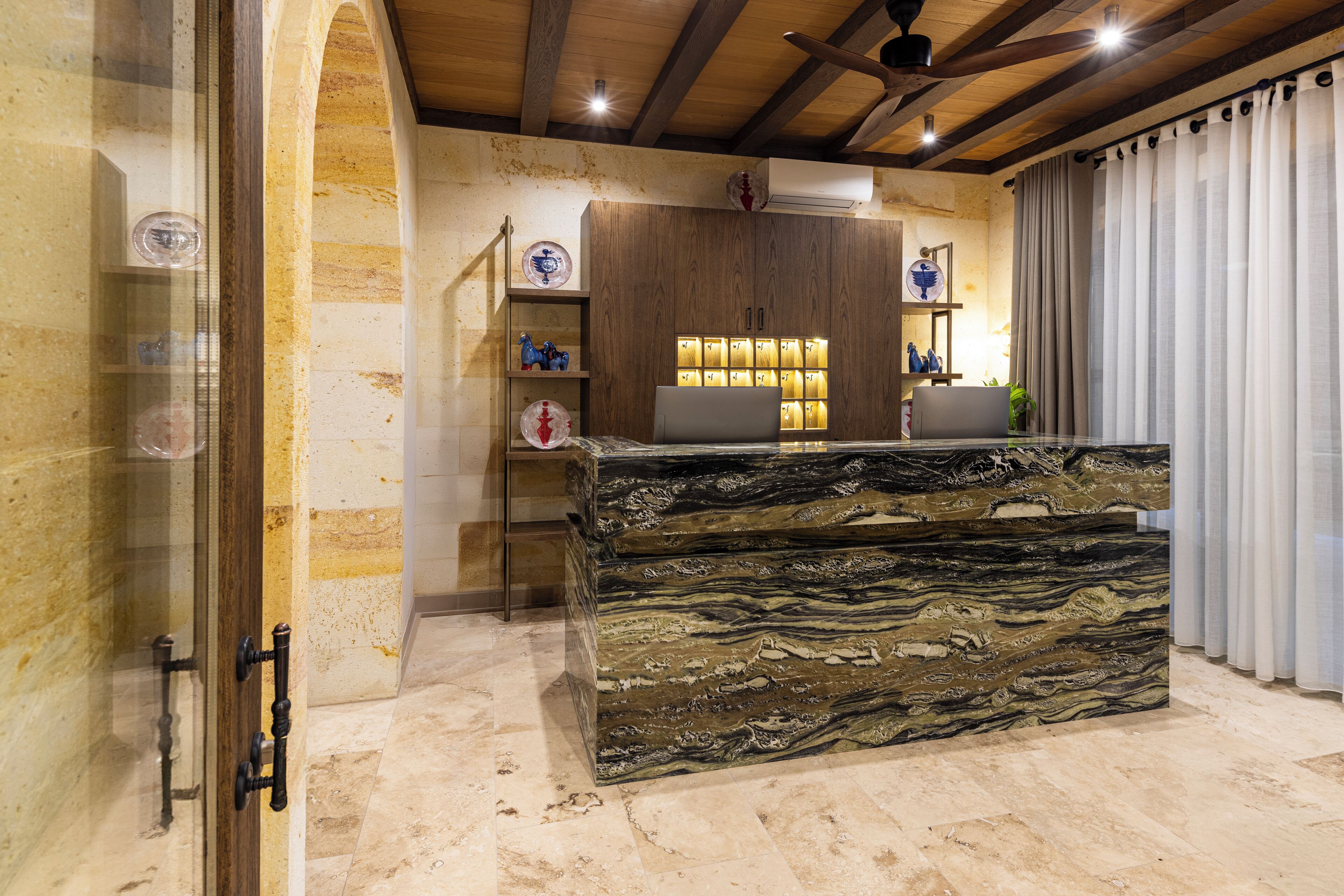 A reception desk with a marble top, wooden cabinets, and a glass display case.