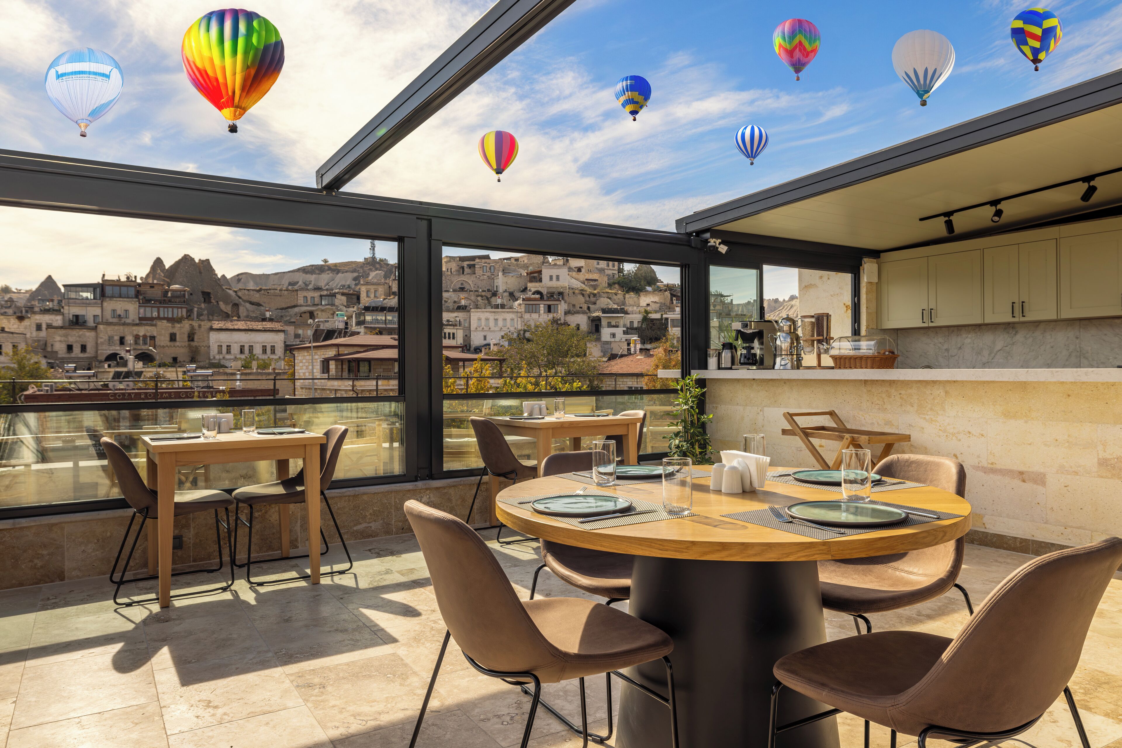 A rooftop terrace with a dining area, large windows, and a view of a cityscape.