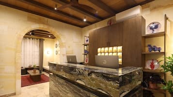 A reception area with a marble counter, wooden cabinets, and a ceiling fan.