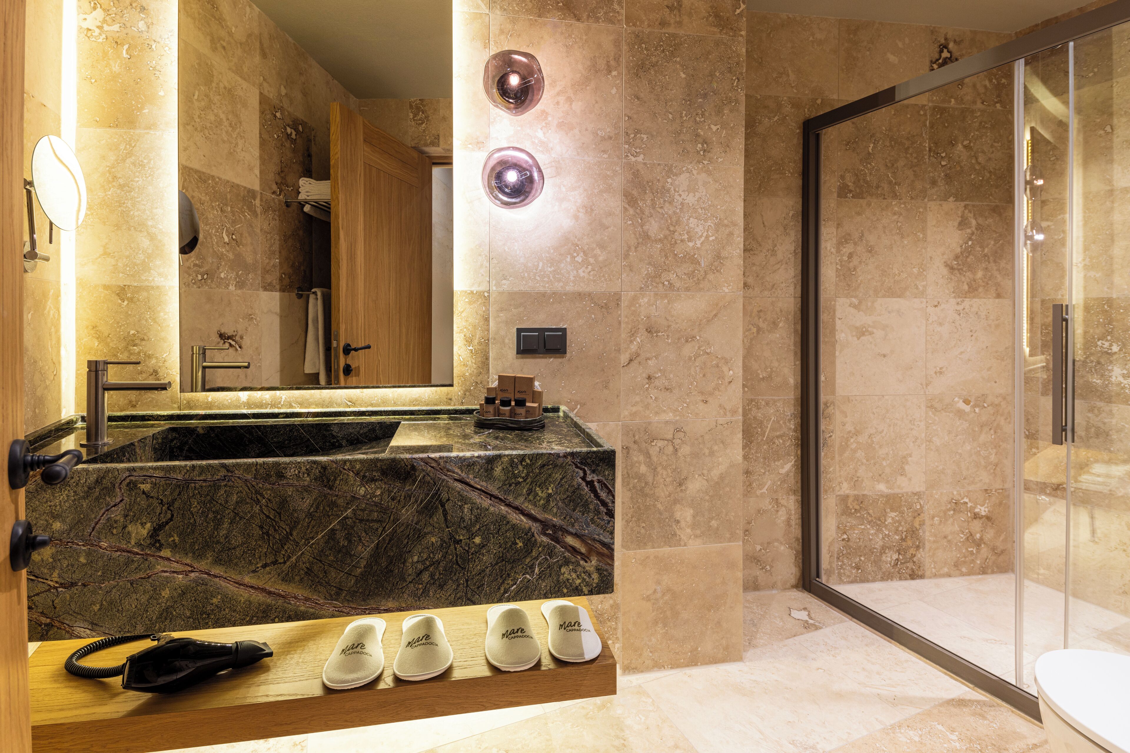 A bathroom with a marble sink, a mirror, and a glass shower enclosure.