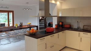 A modern kitchen with a central island, stainless steel range hood, and a built-in oven. There are bar stools and a dining table in the adjacent area. - Torre al Mar: sea view and pool, 150m to the beach, 8 pers., aircon, ETV/5162  (Cala Santanyí)