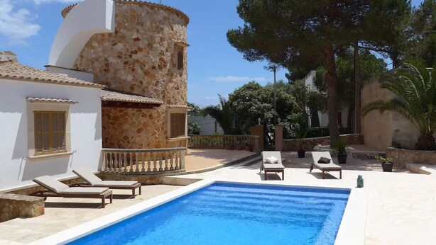 A swimming pool with lounge chairs, a stone tower, and a white building with a window. - Torre al Mar: sea view and pool, 150m to the beach, 8 pers., aircon, ETV/5162  (Cala Santanyí)
