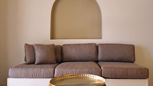Un salon moderne avec un canapé, une arche décorative au mur et deux appliques murales.