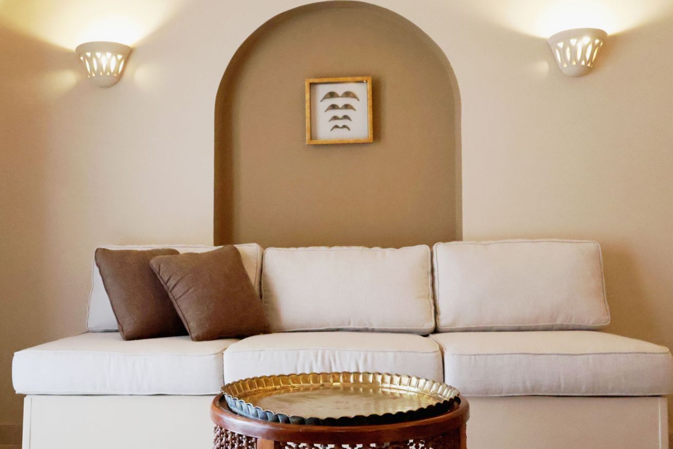 A white sofa with three cushions, a decorative tray, and a framed picture on the wall.