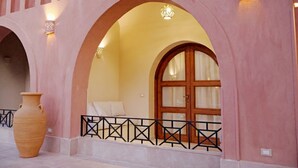 A building with pink arches, a large vase, and a wooden door with glass panels. - Malkata House Ground Floor Suite, Pool & Dine & Tours (Luxor)