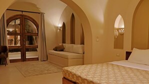 A bedroom with a bed, a sofa, and a window with curtains.