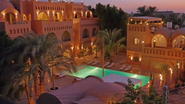 Ein Resort mit Swimmingpool, Palmen und traditioneller Architektur.