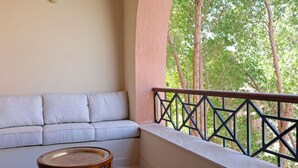 Ein Balkon mit bequemen Sitzmöglichkeiten, einem runden Tisch und Blick auf Bäume.