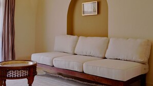 Ein Wohnzimmer mit einer Couch, einem kleinen Holztisch, einem Wandbild und einer Lampe.