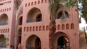 Ein Gebäude mit mehreren Bögen und Balkonen, mit einem Innenhof mit Palmen und Topfpflanzen.