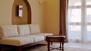 Un soggiorno con un divano, un tavolino rotondo in legno e una cornice appesa al muro.