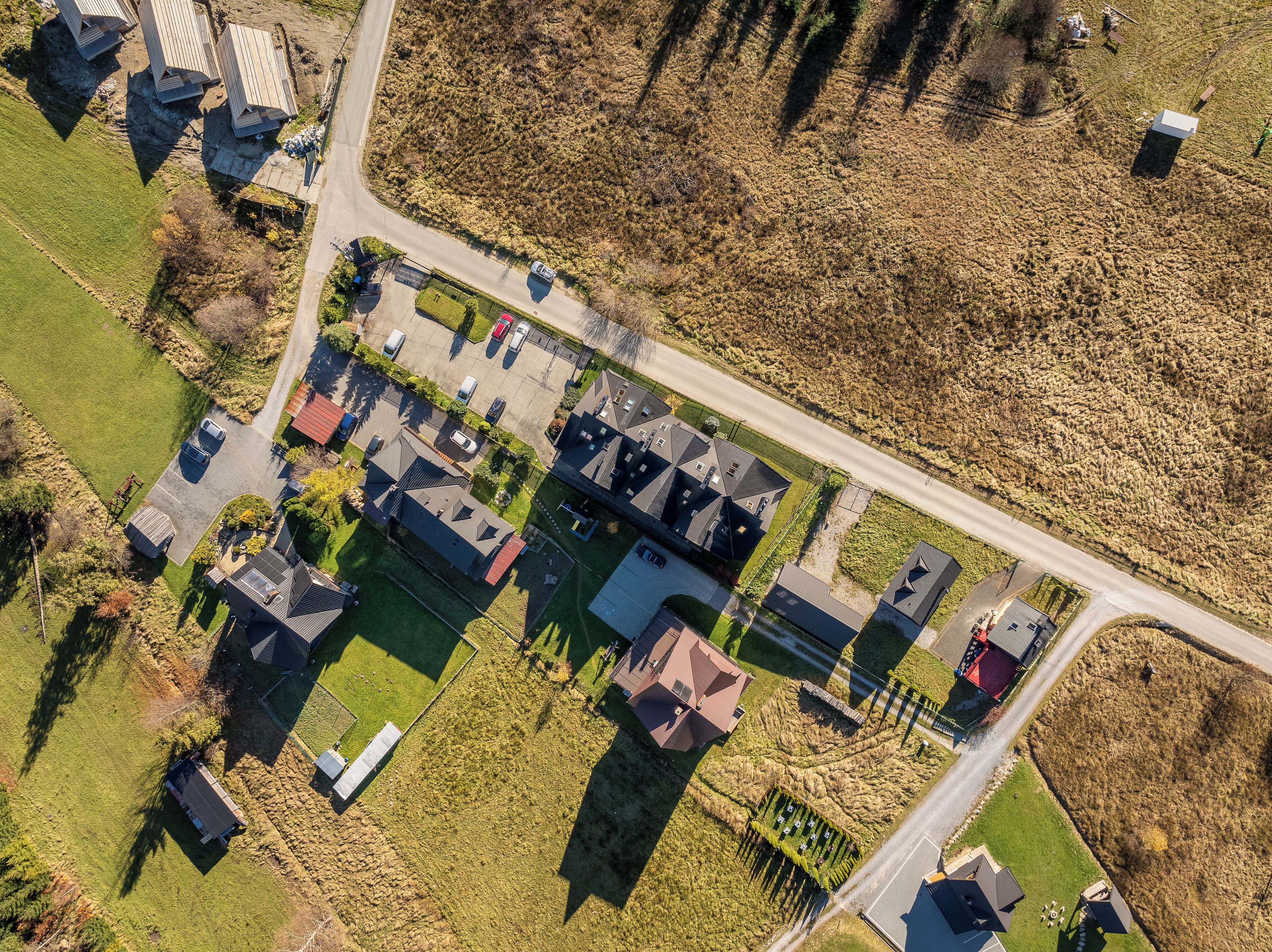 An aerial view of a residential area with houses, a parking lot, and a road.