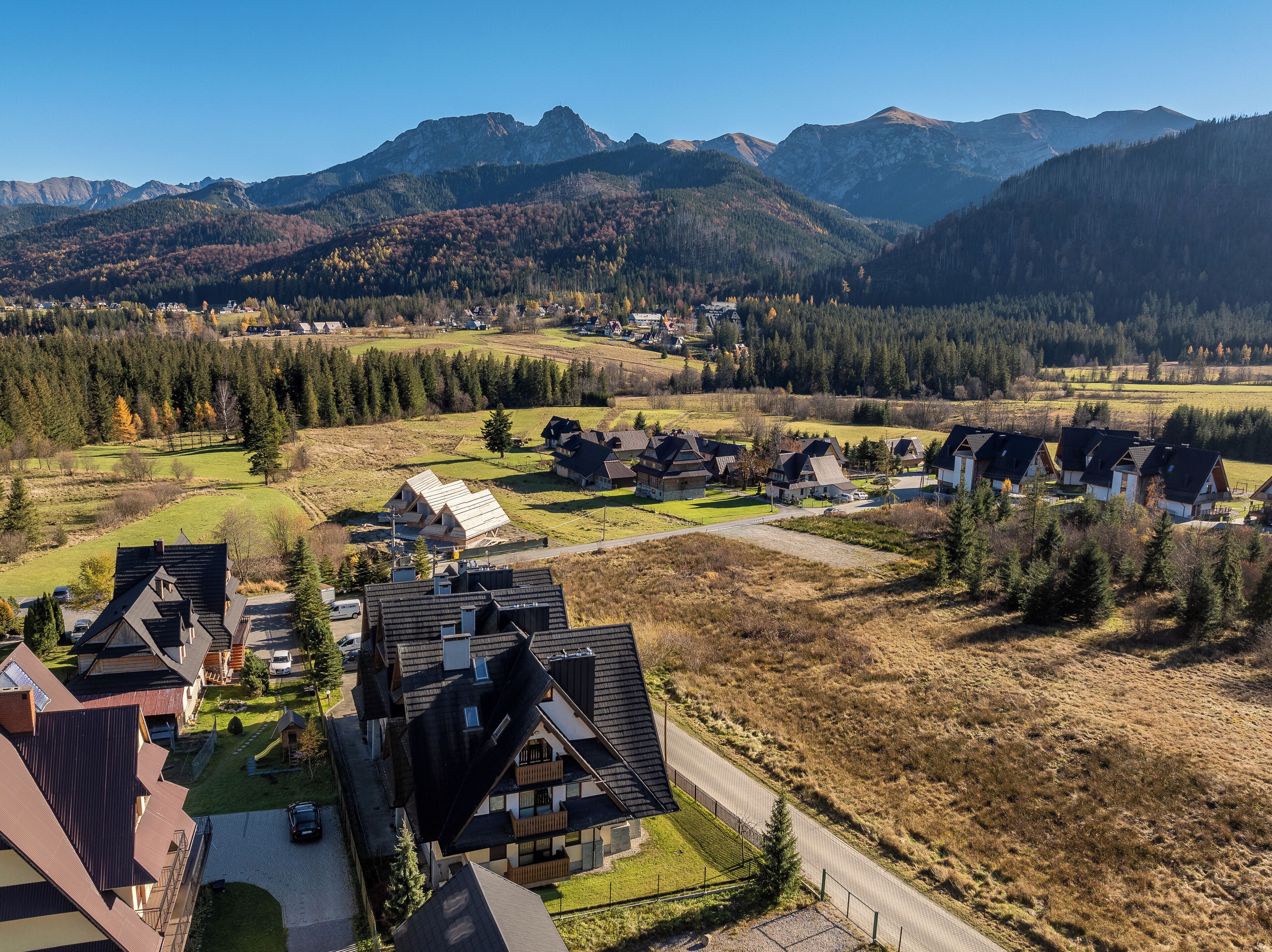Un quartier résidentiel avec des maisons, une route et des montagnes en arrière-plan.