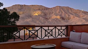 A balcony with a sofa and a small table, overlooking a mountainous landscape.