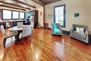 A spacious living area with a dining table, two armchairs, and a sofa.