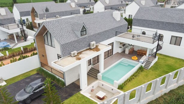 Una casa moderna con piscina, un patio cubierto y un coche aparcado en la entrada.