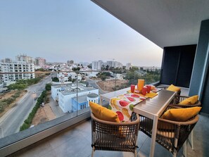 Enjoy al fresco dining on this balcony with a table set amidst a charming residential view.