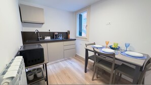 Una cocina compacta con horno integrado, lavamanos y ventana.