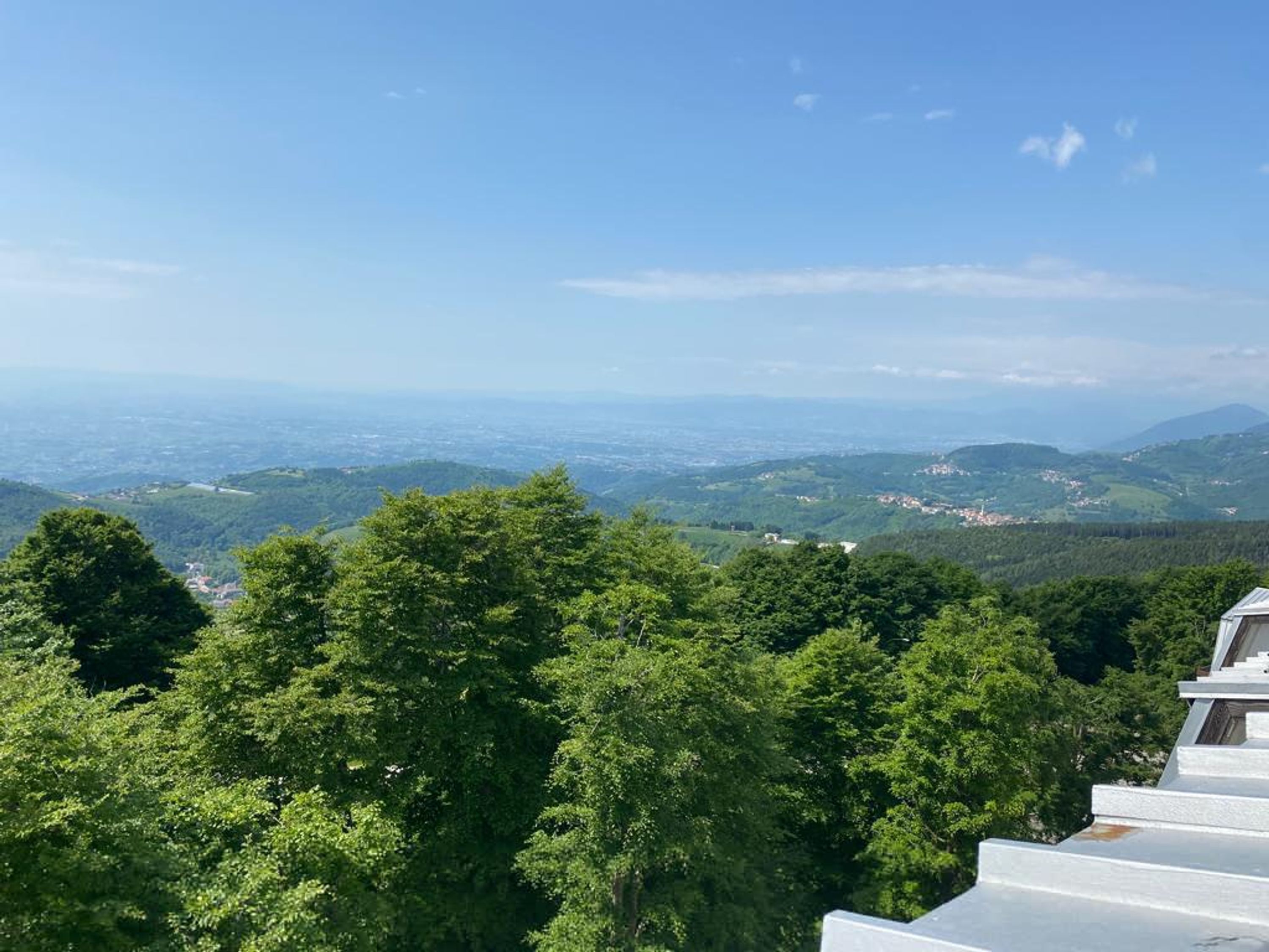 Vista desde un punto elevado que domina un valle cubierto de vegetación densa y edificios a lo lejos.