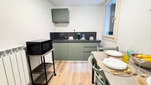 A compact kitchen with a microwave, sink, and a dining area with a table set for two. - Tre Esse Verde by Ca-sa Check (Chioggia)
