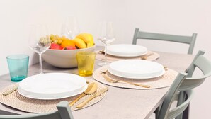 A dining table set with white plates, gold cutlery, and a bowl of fruit. - Tre Esse Verde by Ca-sa Check (Chioggia)