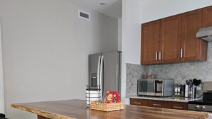 A modern kitchen with a central island, bar stools, stainless steel appliances, and wooden cabinets.