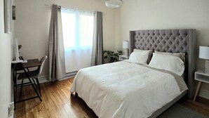 A bedroom with a large bed, a desk, and a chair.