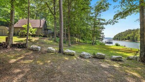 A cabin with a deck overlooking a lake, surrounded by trees and rocks. - Waterfront Beaver Lake Cabin Retreat (Rogers)