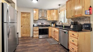 A modern kitchen with wooden cabinets, stainless steel appliances, and a tiled backsplash. - Waterfront Beaver Lake Cabin Retreat (Rogers)