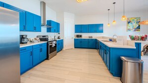 Een moderne keuken met blauwe kastjes, roestvrijstalen apparatuur en een houten vloer.