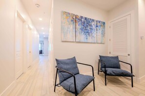 A hallway with two chairs, a ceiling light, and a door with louvered shutters.