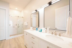 Une salle de bain moderne avec deux lavabos, un grand miroir et une douche à l’italienne.
