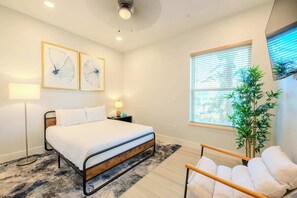 A bedroom with a bed, bedside table, lamp, and a window with blinds.