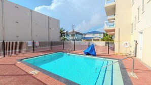 En swimmingpool med et afspærret område, en livredderstand og et overdækket siddeområde.