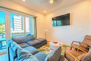Una sala de estar moderna con sofá, sillón y televisor de pantalla plana montado en la pared.