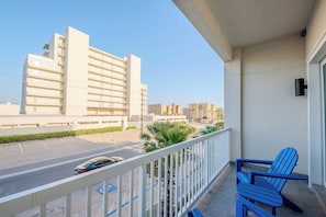 A balcony with a view of a parking lot and buildings.