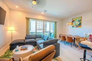 A modern living room with a sectional sofa, a round coffee table, and a dining area with a table and chairs. - Surfside Sanctuary (South Padre Island)