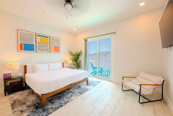 A bedroom with a bed, a nightstand, a chair, and a balcony with a view.