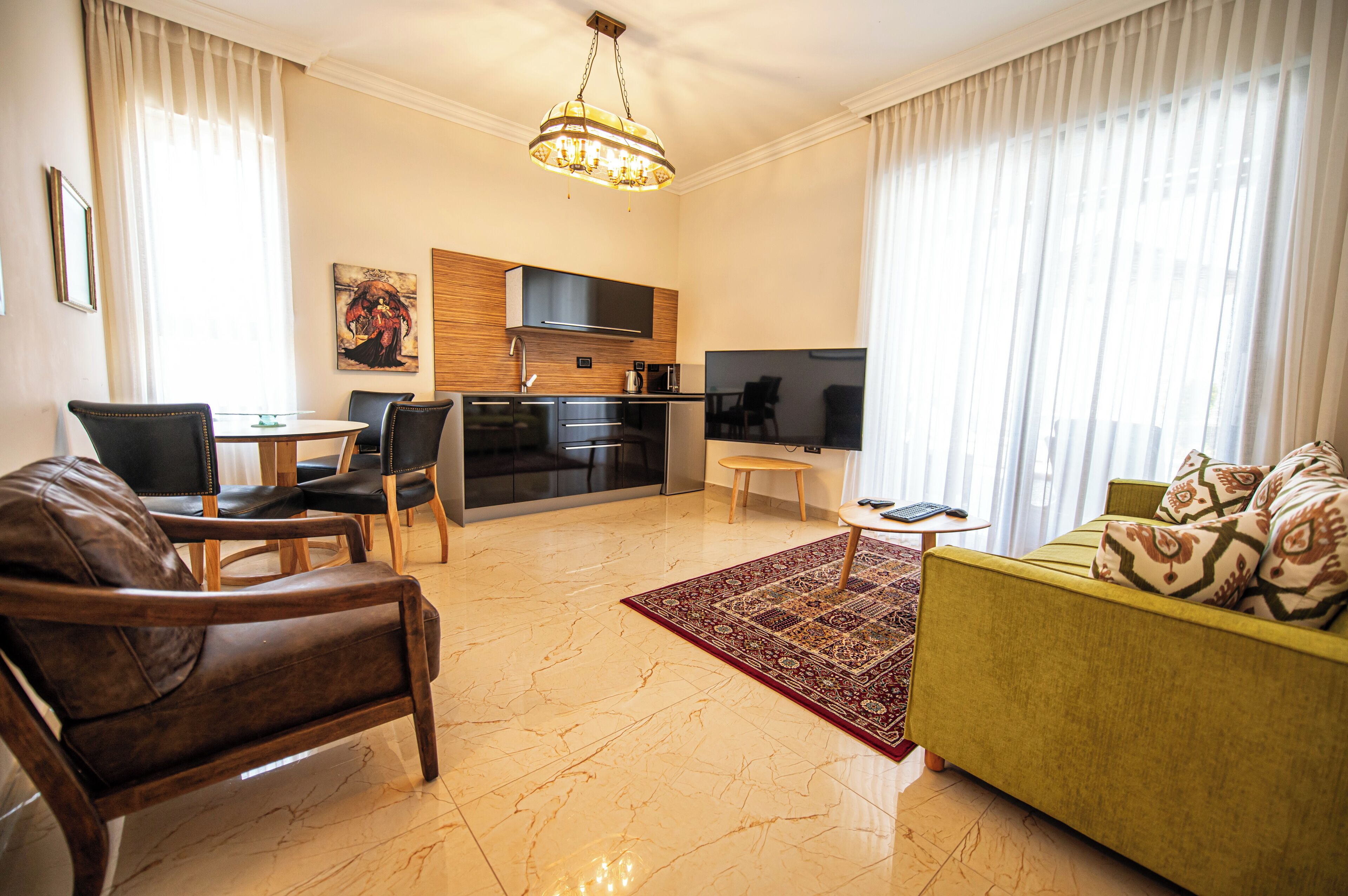 Una sala moderna con sofá, sillones, una mesa de centro, televisor, área de cocina y mesa de comedor.