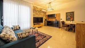 Een moderne woonkamer met een bank, televisie en een eethoek.